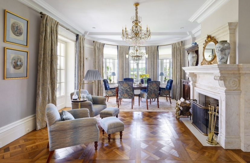 Salon i jadalnia w klasycznej rezydencji pod Warszawą, z marmurowym kominkiem, kryształowym żyrandolem i tkaninami Zoffany oraz William Morris, projekt Kanach Interiors.