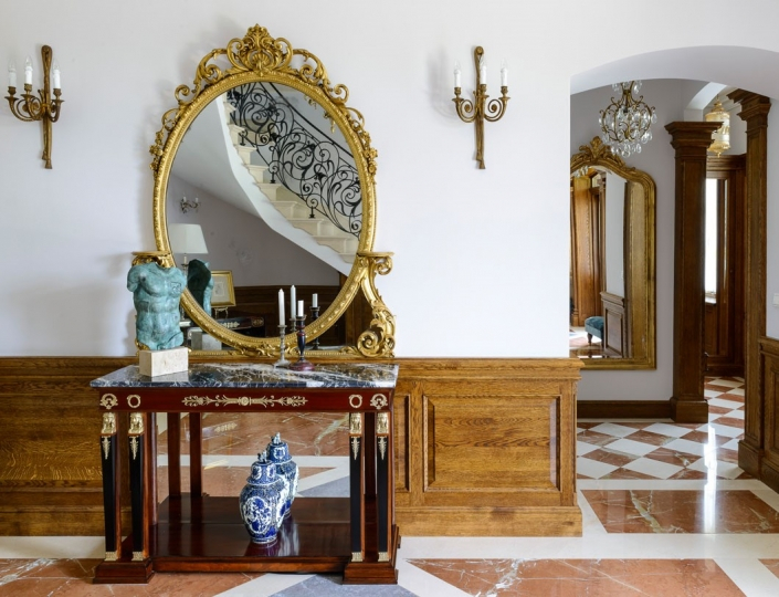 Hol wejściowy z podłogą z dwóch odcieni marmuru z antyczną konsolą i złoconym lustrem, projekt Kanach Interiors.”