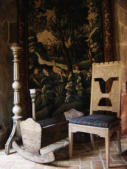 Historyczna kołyska na tle XVIII-wiecznej werdiury francuskiej. Jadalnia z dużym kominkiem i stół z żakardową tapiserią. Projekt wnętrza KANACH INTERIORS