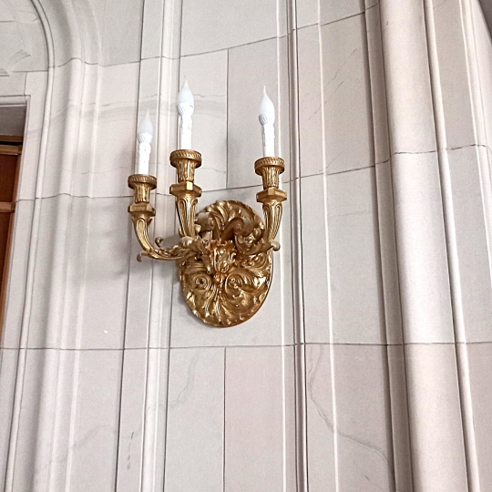 Kinkiet trójramienny na ścianie klatki schodowej wykonany według projektu Ewy Kanach, Pałac Karola Poznańskiego w Łodzi