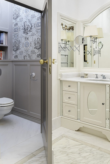 Łazienka w stylu klasycznym, wykończona marmurem Carrara i Calacatta, Na drugim planie WC z drewnianym panelingiem i francuską tapetą historyczną. Projekt łazienki KANACH INTERIORS Projekt wnętrza KANACH INTERIORS